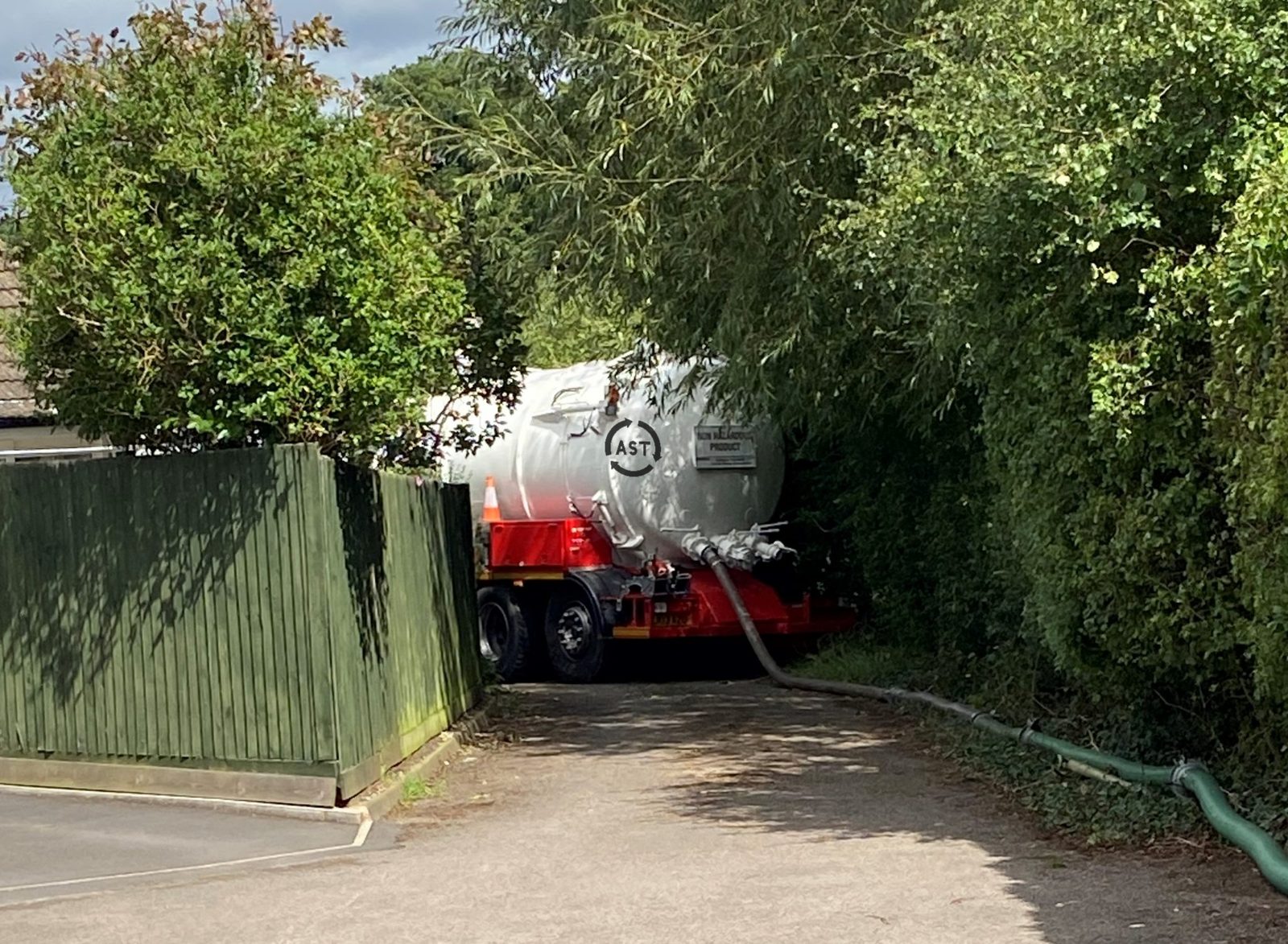 AST Transport vacuum tanker emptying a septic tank from a residential driveway